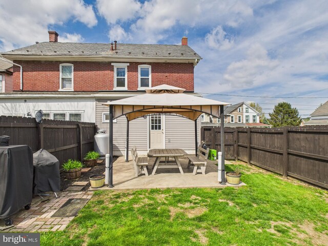 back of house with a gazebo, a chimney, a lawn, a fenced backyard, and a patio
