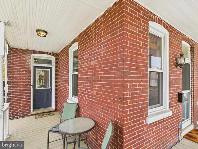 view of exterior entry featuring brick siding and covered porch