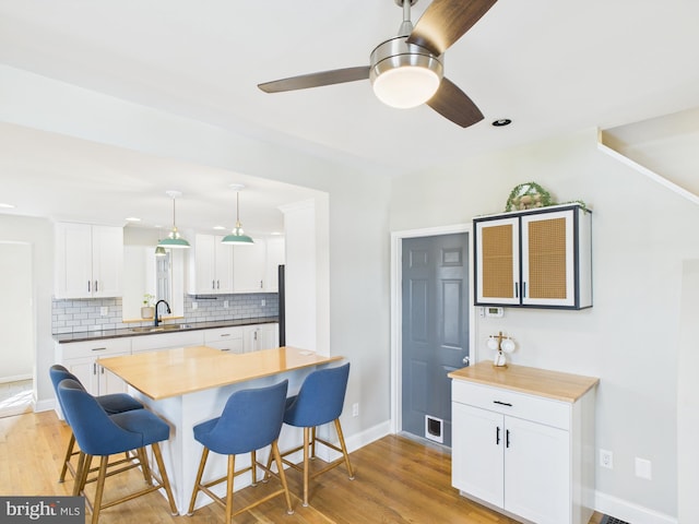 kitchen with backsplash, a ceiling fan, a sink, and a breakfast bar
