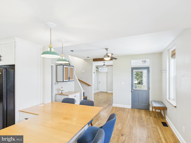dining area featuring baseboards, visible vents, light wood-style floors, a ceiling fan, and stairway