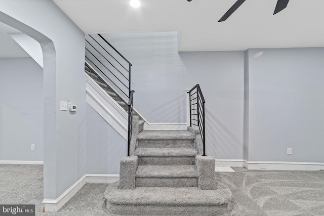 stairs with carpet floors, a ceiling fan, and baseboards