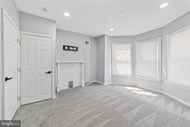 unfurnished living room featuring baseboards, visible vents, carpet, and recessed lighting