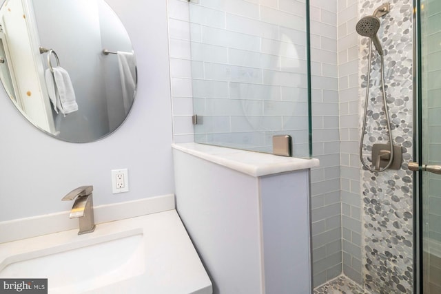 bathroom with a tile shower and vanity