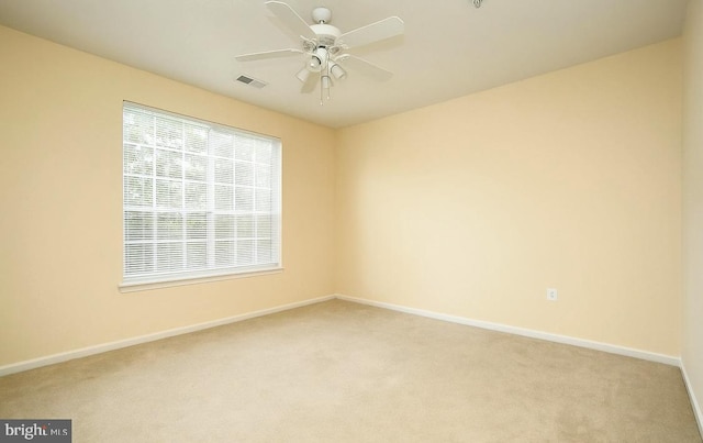 spare room with baseboards, light carpet, and ceiling fan