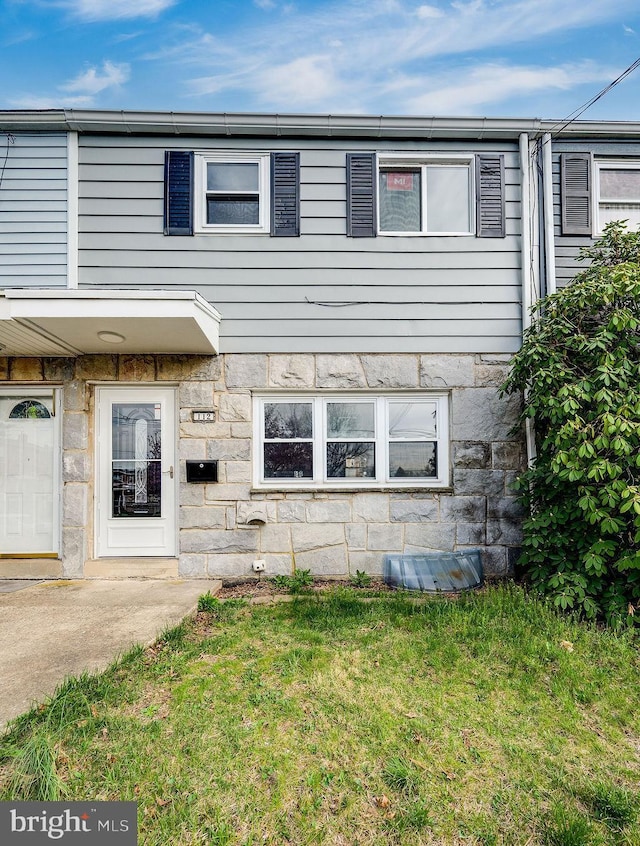 townhome / multi-family property featuring stone siding and a front yard
