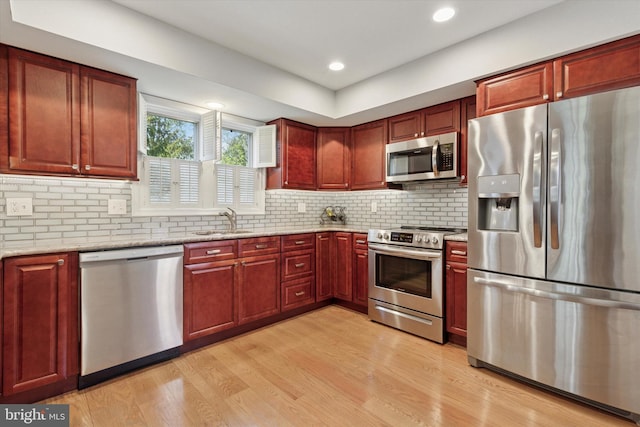 kitchen with a sink, dark brown cabinets, appliances with stainless steel finishes, and light wood-style floors