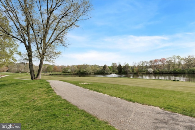 view of property's community with a lawn, a water view, and golf course view