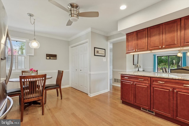 kitchen with light wood finished floors, crown molding, a ceiling fan, visible vents, and hanging light fixtures