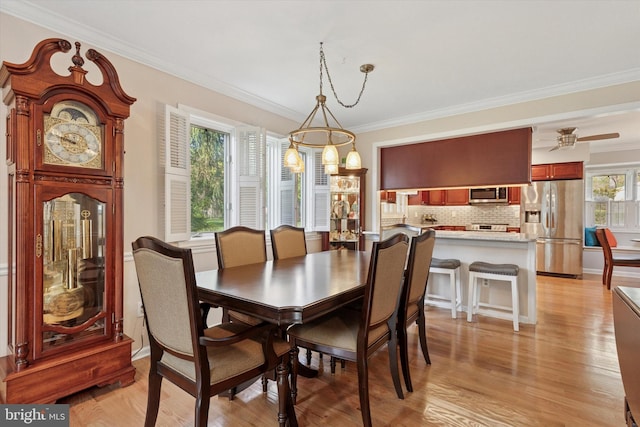 dining space with ornamental molding and light wood finished floors