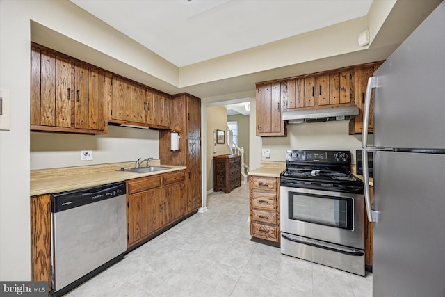 kitchen with a sink, appliances with stainless steel finishes, under cabinet range hood, and light countertops