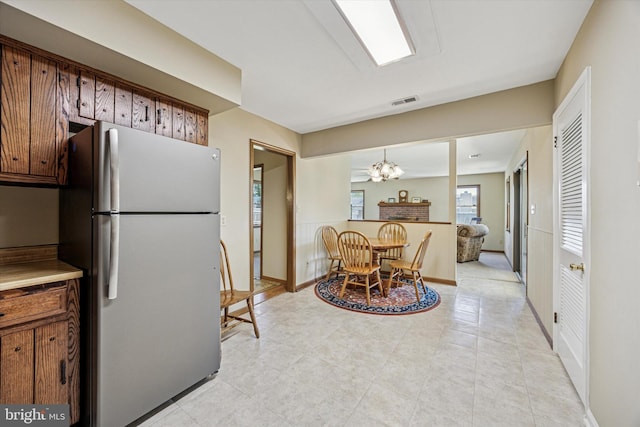 kitchen featuring baseboards, freestanding refrigerator, and a chandelier
