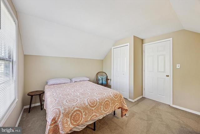 bedroom with a closet, carpet flooring, baseboards, and lofted ceiling