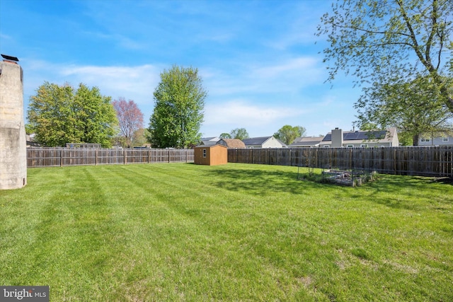 view of yard featuring a storage shed, an outbuilding, and a fenced backyard
