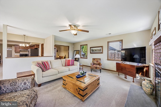 living room with visible vents, light colored carpet, a fireplace, baseboards, and ceiling fan with notable chandelier