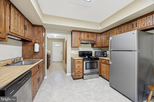 kitchen featuring a sink, appliances with stainless steel finishes, under cabinet range hood, and brown cabinets