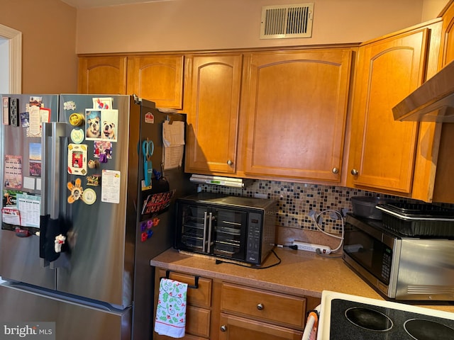 kitchen with a toaster, visible vents, decorative backsplash, brown cabinetry, and appliances with stainless steel finishes