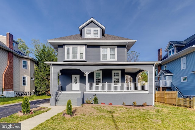 traditional style home with a porch, fence, and a front yard
