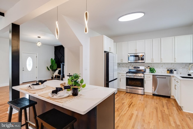 kitchen with appliances with stainless steel finishes, decorative backsplash, a sink, and light wood-style flooring