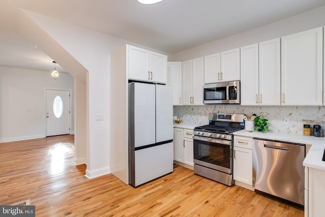 kitchen featuring light countertops, stainless steel appliances, backsplash, and light wood-style floors
