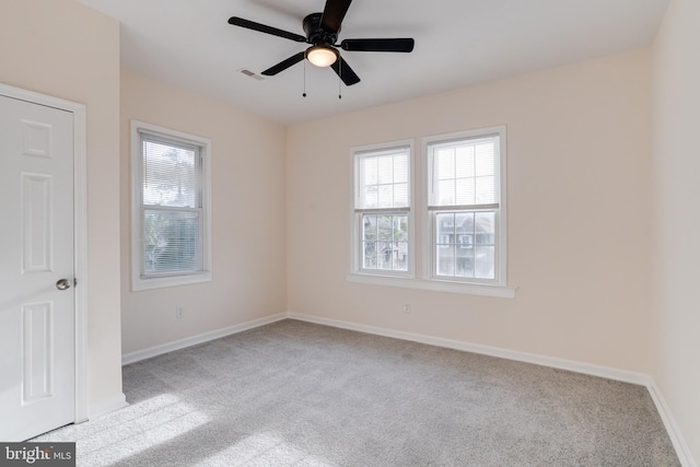 carpeted spare room featuring a ceiling fan, baseboards, visible vents, and plenty of natural light