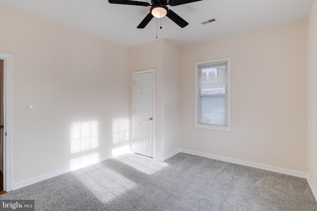 spare room featuring carpet floors, a ceiling fan, baseboards, and visible vents