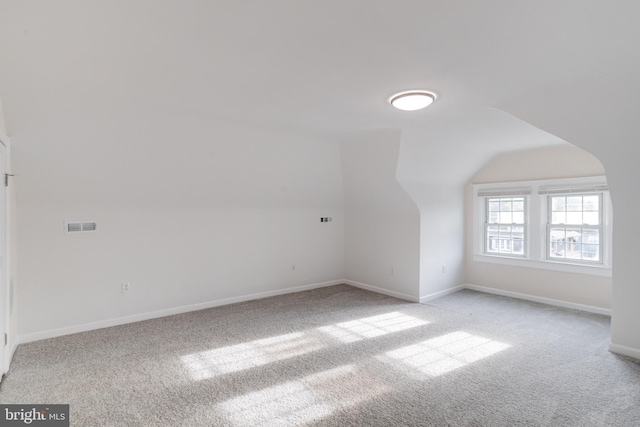 additional living space featuring carpet flooring, baseboards, visible vents, and vaulted ceiling