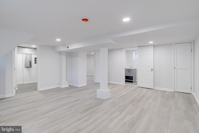 finished basement with recessed lighting, baseboards, light wood finished floors, and electric panel