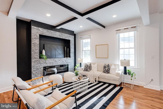 living area featuring wood finished floors, beamed ceiling, baseboards, a stone fireplace, and recessed lighting