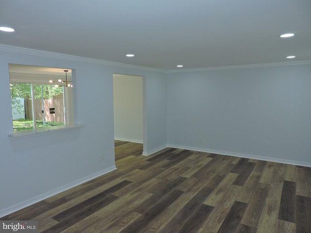 empty room featuring a chandelier, recessed lighting, crown molding, dark wood-type flooring, and baseboards