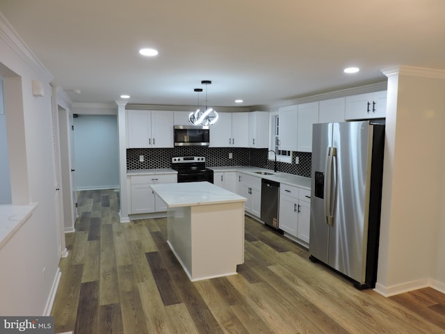 kitchen with stainless steel appliances, a sink, backsplash, white cabinetry, and a kitchen island