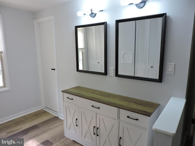 bathroom with wood finished floors, a closet, baseboards, and vanity