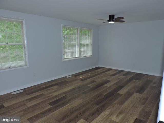 empty room with a ceiling fan, dark wood-type flooring, and baseboards