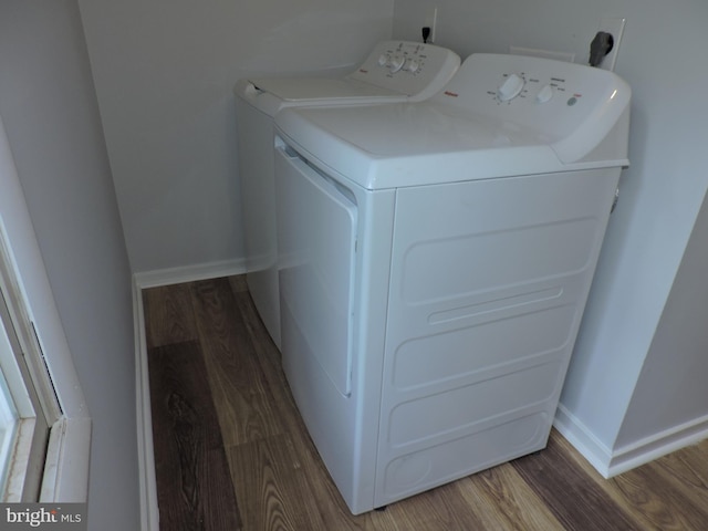 clothes washing area with separate washer and dryer, wood finished floors, and baseboards