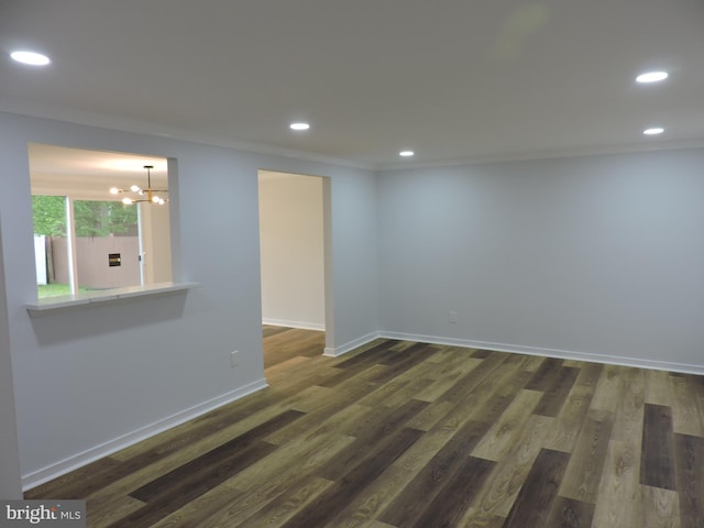 empty room with ornamental molding, a chandelier, recessed lighting, dark wood finished floors, and baseboards
