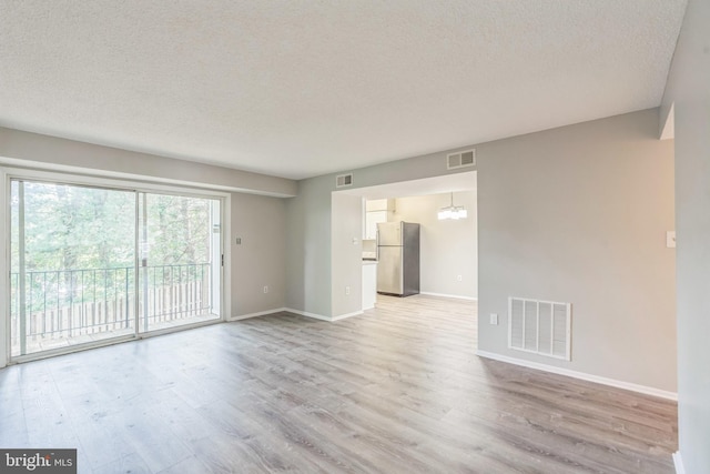7743 Inversham Dr Unit 197, Falls Church, VA 22042 - unfurnished living room featuring a textured ceiling, light wood-style flooring, and a chandelier