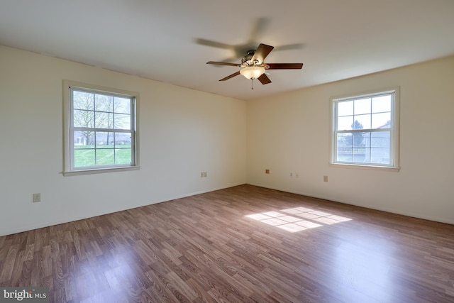 unfurnished room with a ceiling fan, wood finished floors, and a healthy amount of sunlight