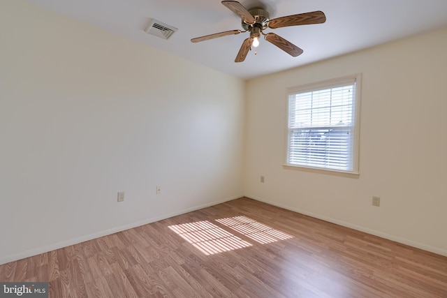 unfurnished room with baseboards, wood finished floors, visible vents, and ceiling fan