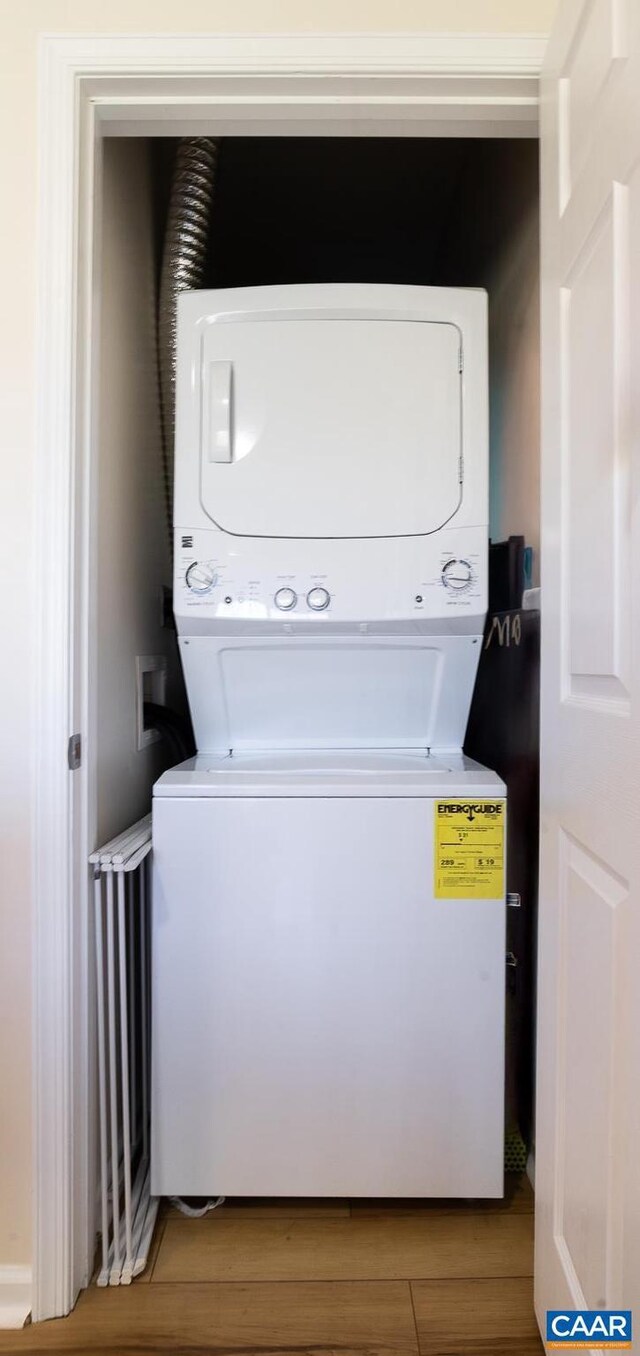 laundry area featuring light wood-type flooring, stacked washer / dryer, and laundry area