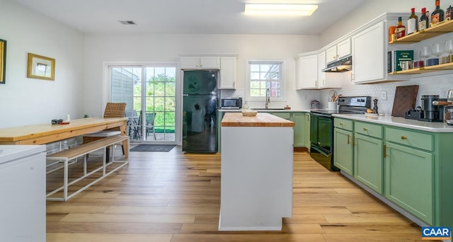 kitchen with green cabinetry, visible vents, a sink, a center island, and black appliances