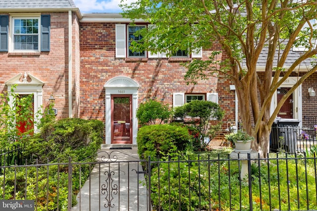 multi unit property featuring brick siding and a fenced front yard
