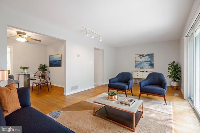living room featuring track lighting, visible vents, light wood-style floors, baseboards, and ceiling fan
