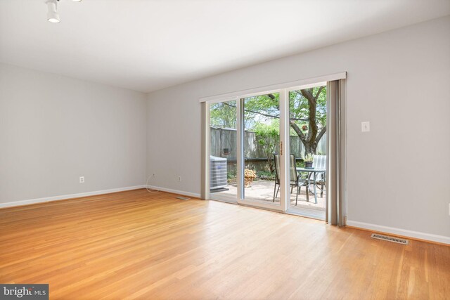 spare room featuring visible vents, light wood-style floors, and baseboards