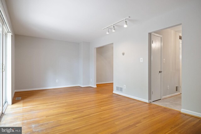 spare room featuring visible vents, baseboards, light wood finished floors, and track lighting