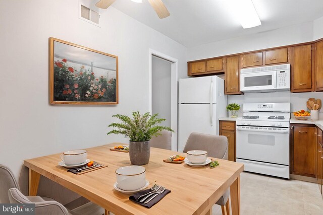 kitchen featuring visible vents, brown cabinetry, white appliances, light countertops, and a ceiling fan
