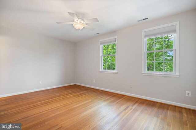 unfurnished room featuring baseboards, visible vents, ceiling fan, and light wood-style floors