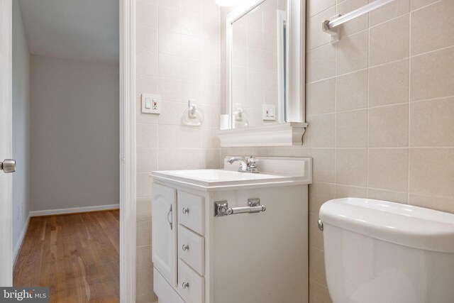 bathroom with toilet, tile walls, wood finished floors, and vanity
