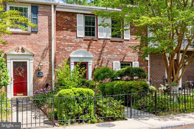 townhome / multi-family property featuring brick siding, a gate, and a fenced front yard