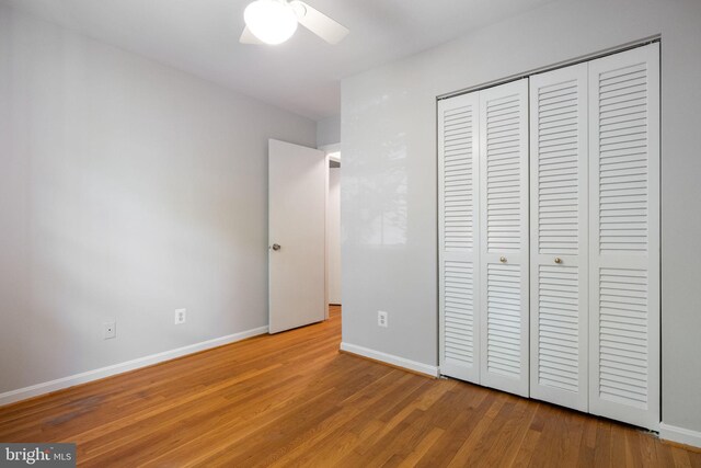 unfurnished bedroom featuring baseboards, ceiling fan, wood finished floors, and a closet