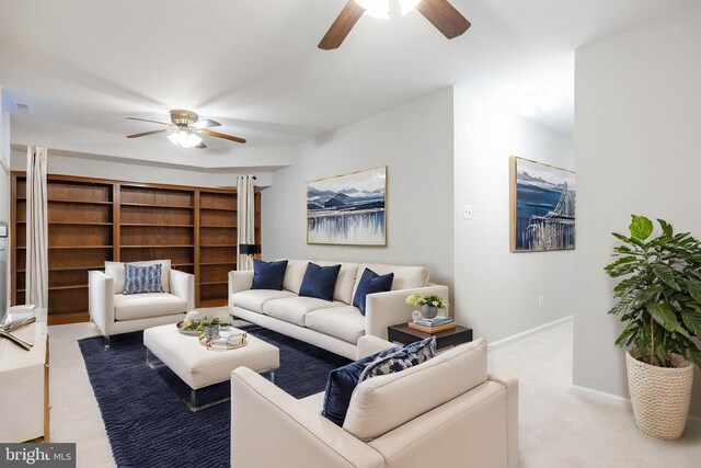 living area featuring a ceiling fan, baseboards, and carpet