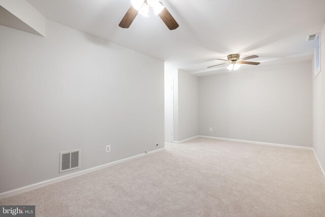 empty room with ceiling fan, visible vents, light carpet, and baseboards